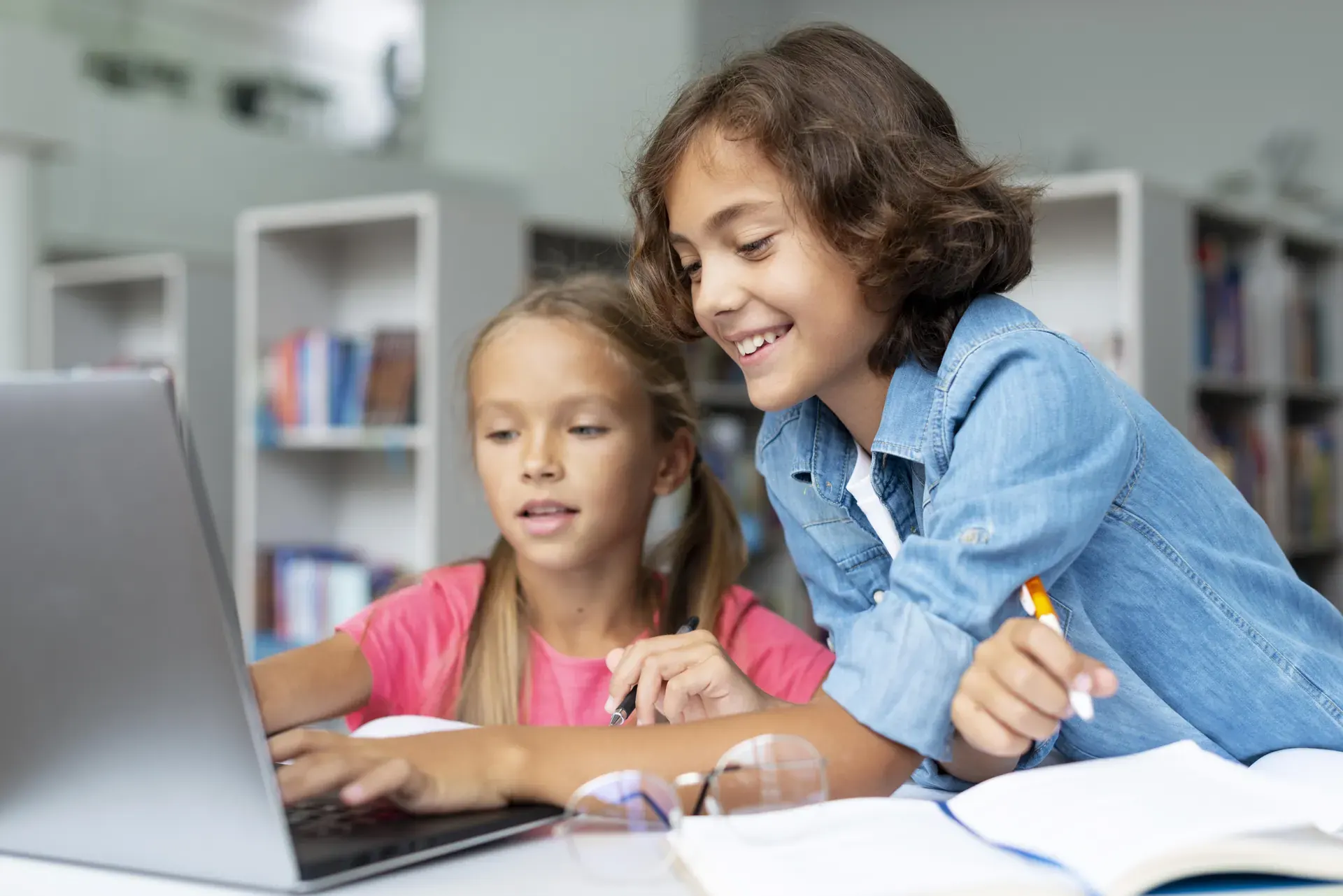 Zwei Kinder lernen gemeinsam an einem Laptop in der Bibliothek